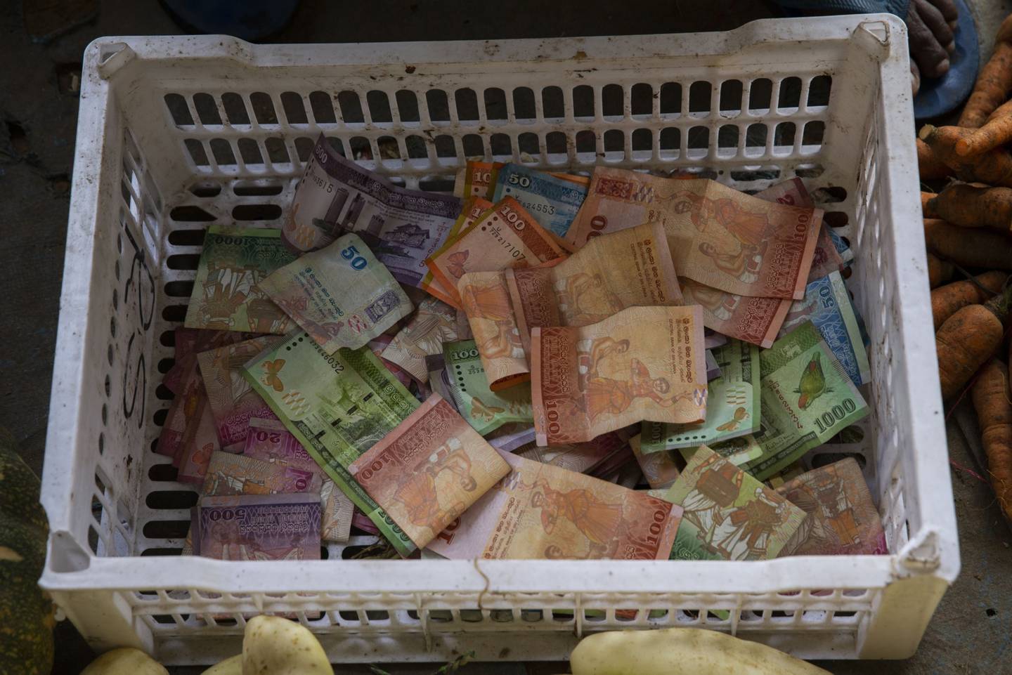 Billetes de banco de Sri Lanka, en un contenedor en un puesto de verduras.