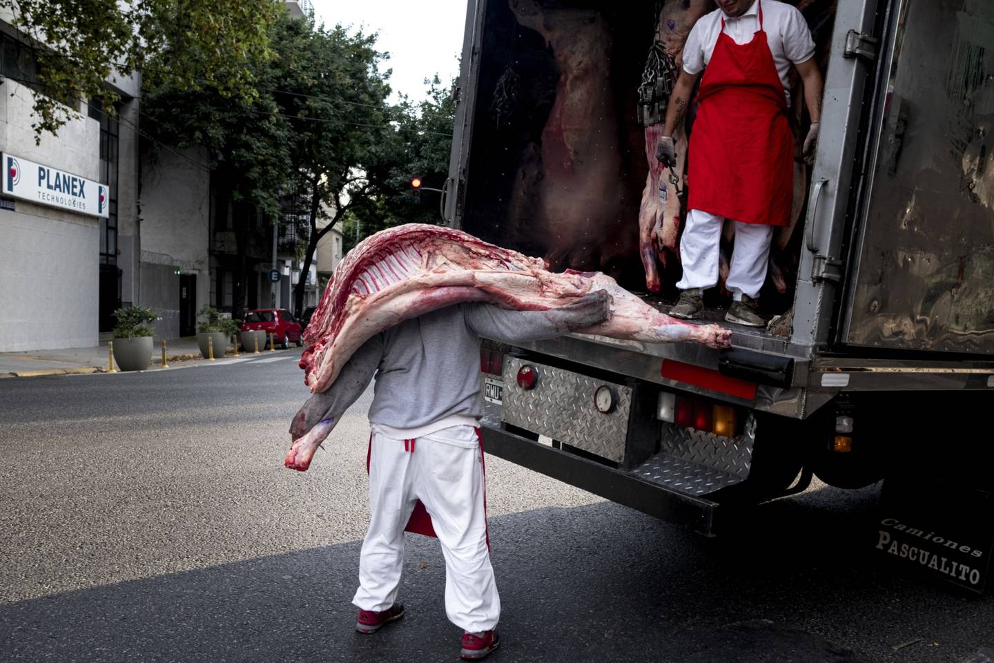 A worker carries a side of beef out of a refrigerated truck to a butcher's shop in Buenos Aires, Argentina.
