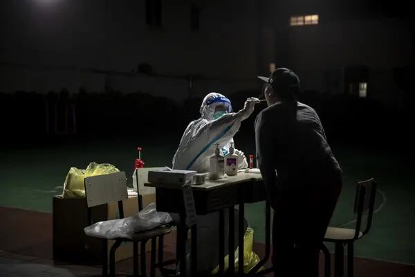 Un trabajador sanitario hisopa a una persona en Shanghái