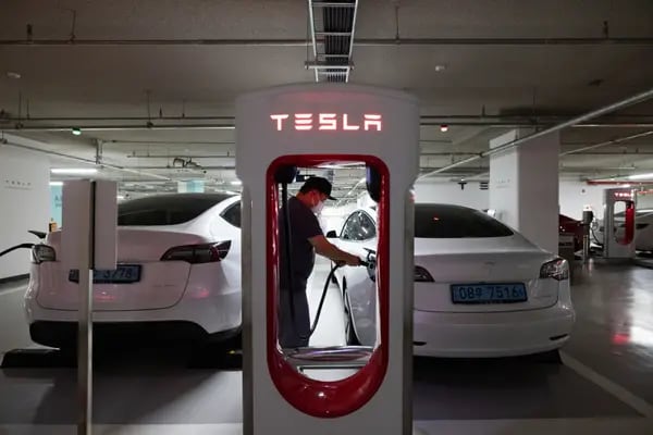 Un conductor carga un Tesla, Modelo 3.
