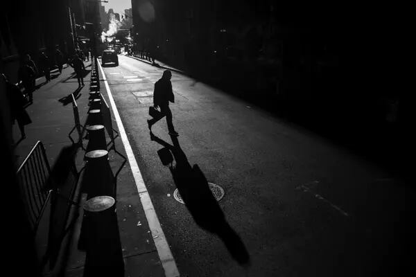 Homem com valise atravessando a rua, a foto está em branco e preto