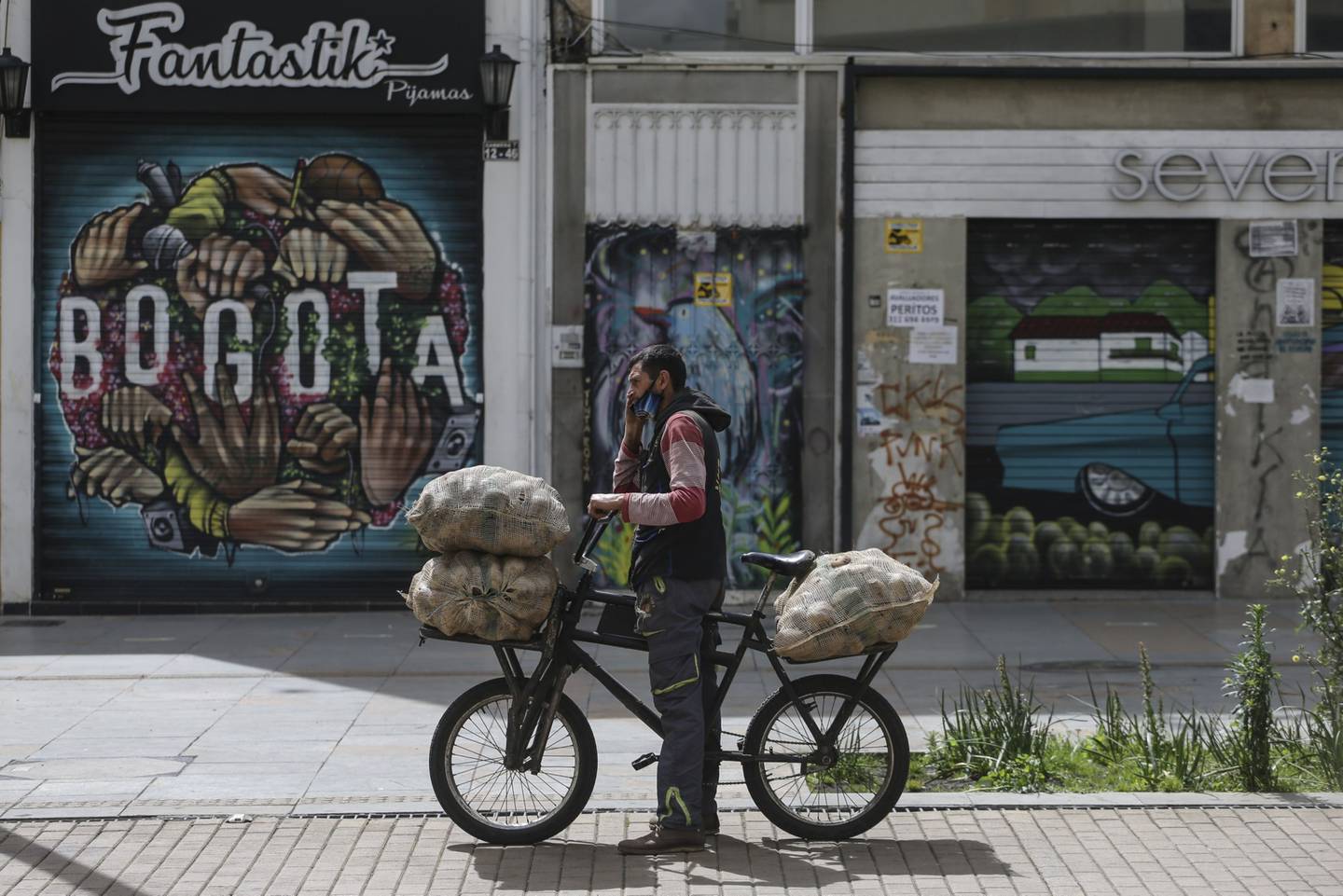 Un mensajero en bicicleta lleva sacos de papa durante una huelga nacional en Bogotá, Colombia, el lunes 21 de septiembre de 2020.