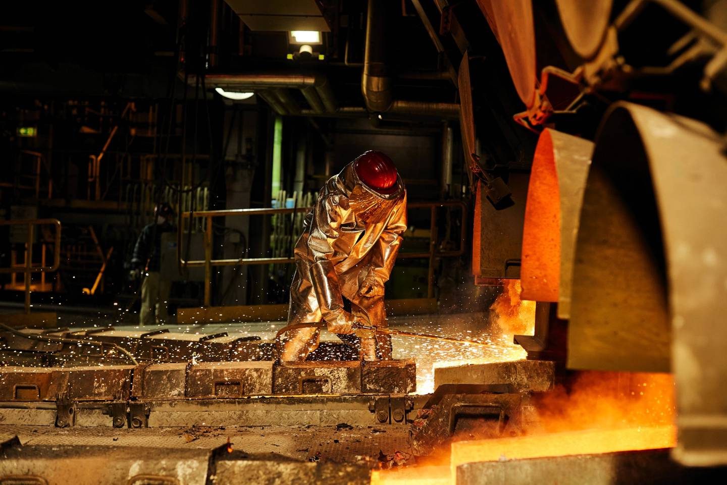 Un trabajador con ropa protectora resistente al calor abre un horno en la planta de fundición de cobre KGHM Polska Miedz SA en Glogow, Polonia, el martes 9 de marzo de 2021. E