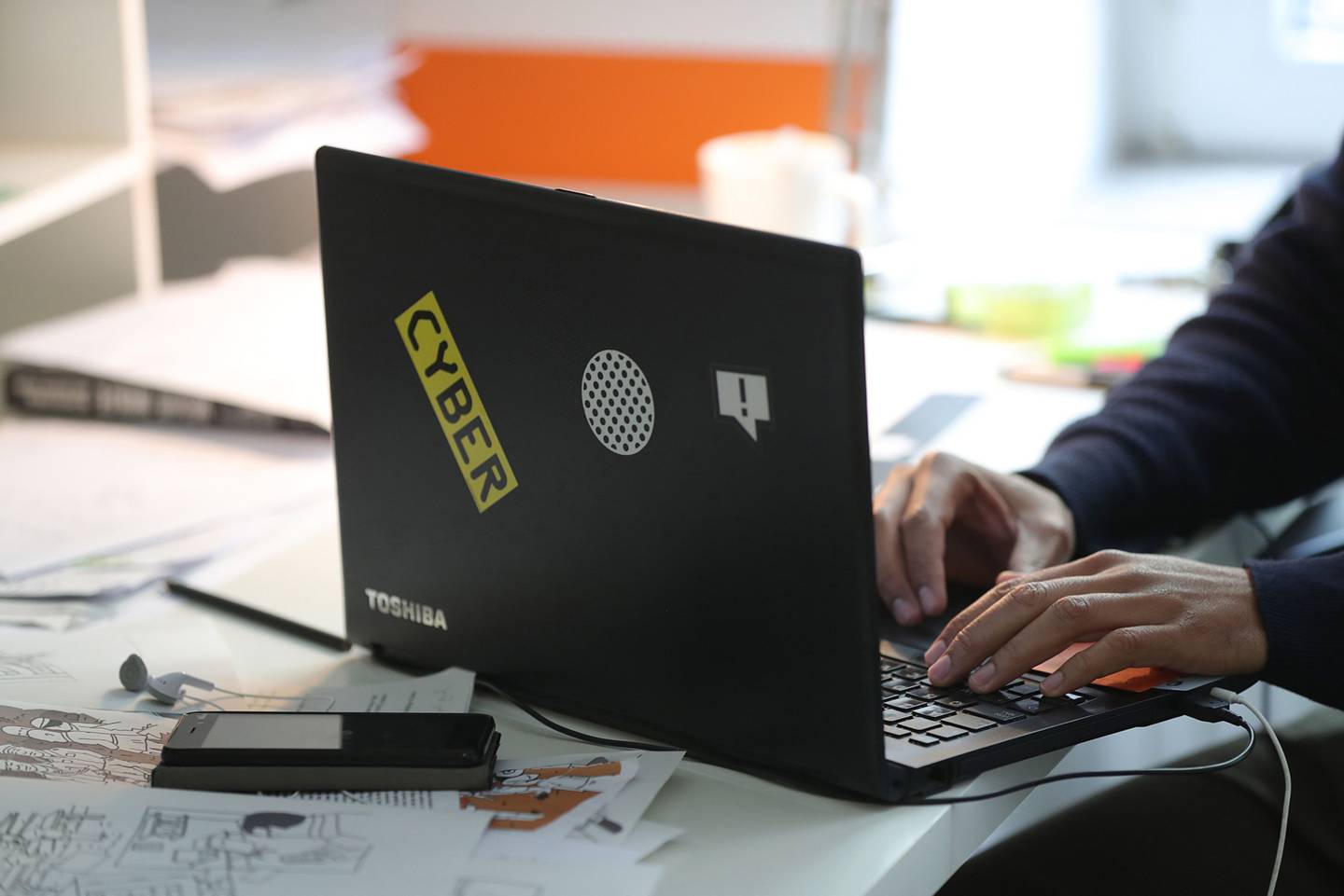Un empleado utiliza un portátil Toshiba Corp. decorado con una pegatina "Cyber".