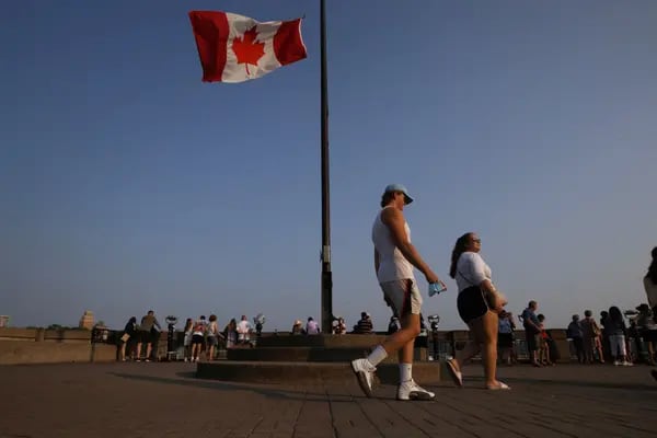 Una bandera de Canadá ondea mientras los turistas visitan las Cataratas del Niágara, Ontario, Canadá, el lunes 9 de agosto de 2021.