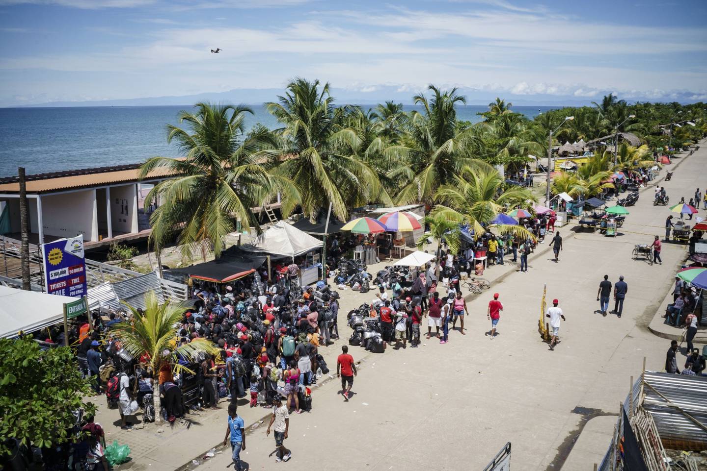 Migrantes esperan para abordar botes en un puerto de la región colombiana de Necoclí.