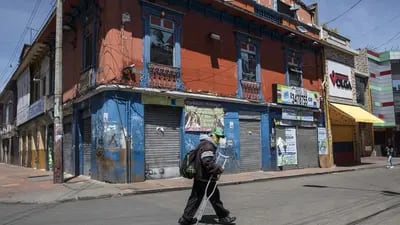 Un peatón con una máscara protectora pasa frente a tiendas cerradas temporalmente para contener la pandemia de covid-19 en Bogotá, Colombia, el sábado 25 de abril de 2021.