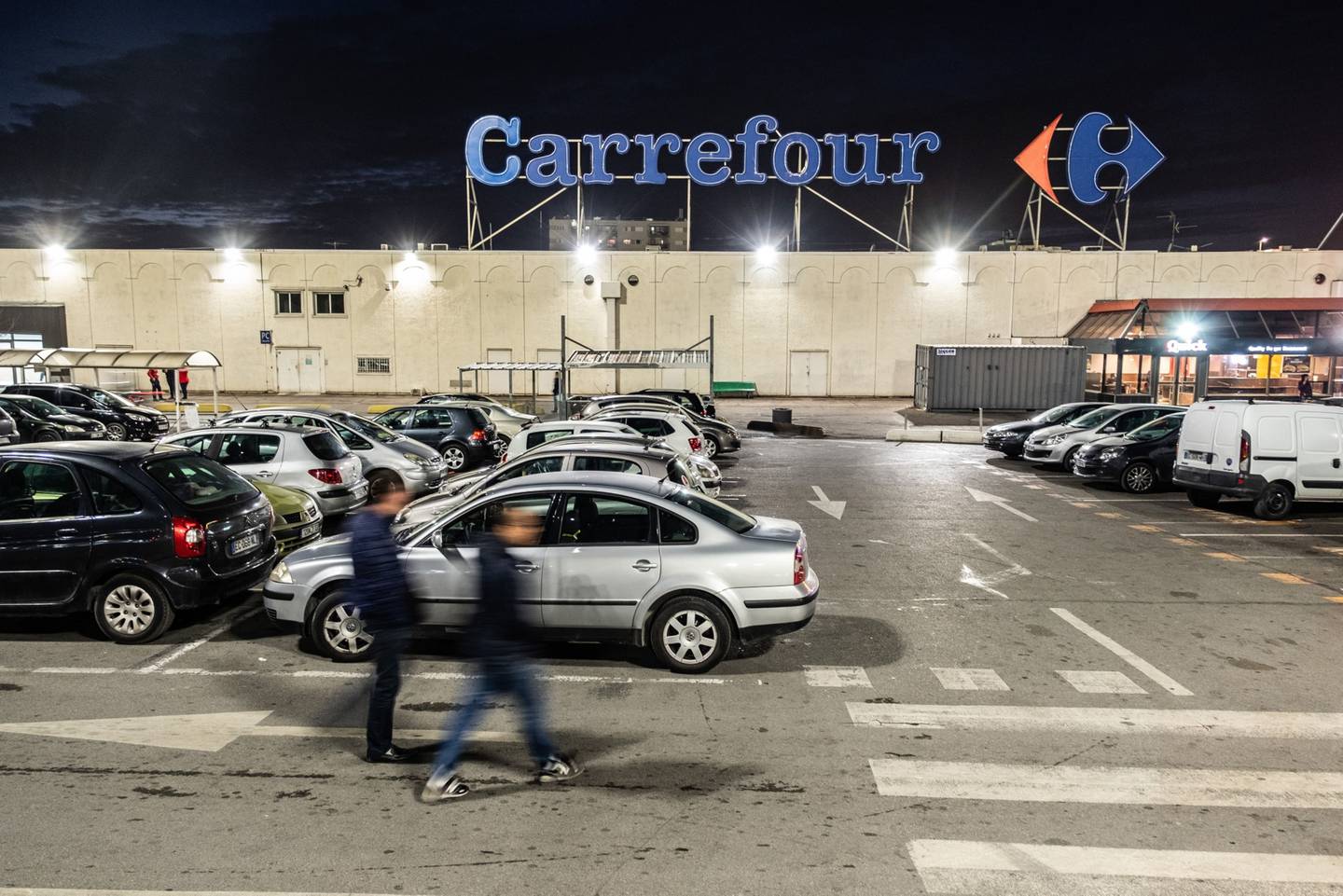 Los peatones caminan en el estacionamiento fuera de una tienda de hipermercado Carrefour SA en la noche en Marsella, Francia, el jueves 17 de enero de 2019. Las acciones de los minoristas franceses, incluyendo Carrefour, Fnac Darty y Maisons du Monde, podrían moverse después de que Casino Guichard-Perrachon SA informara de un conjunto de ventas del cuarto trimestre que superó las estimaciones a pesar de las protestas de los Chalecos Amarillos que amortiguaron los ingresos.