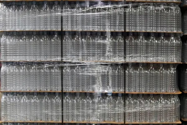 Botellas de plástico vacías sobre paletas en una planta embotelladora.