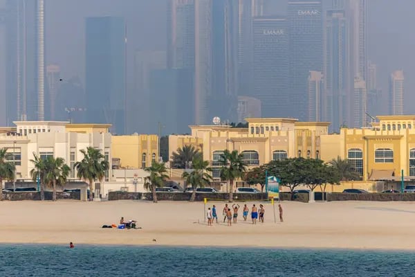 Unos bañistas juegan voleibol, con las viviendas y los rascacielos comerciales como telón de fondo, en el distrito de Jumeirah Beach de Dubai, Emiratos Árabes Unidos, el viernes 25 de agosto de 2023.