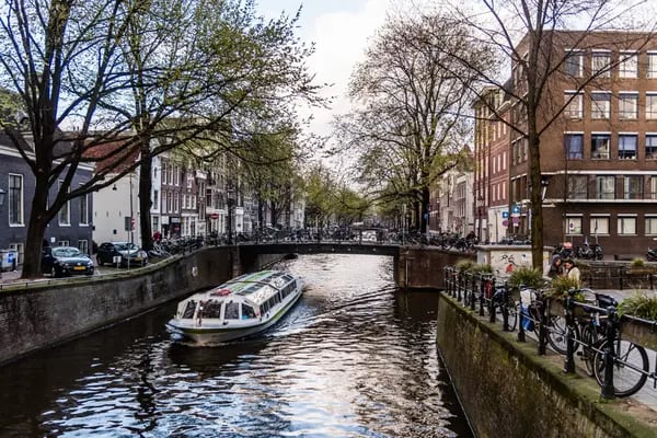 Un barco turístico viaja por un canal de Ámsterdam, Países Bajos.