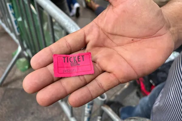 A migrant holds a small paper ticket given to him by authorities to mark his place in the queue for the shelter in front of the Hotel Roosevelt on Tuesday.