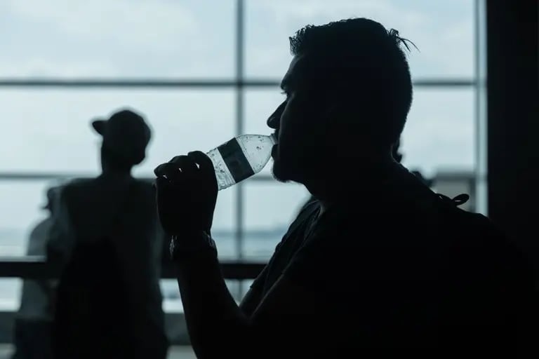 Homem toma água em garrafa plásticadfd