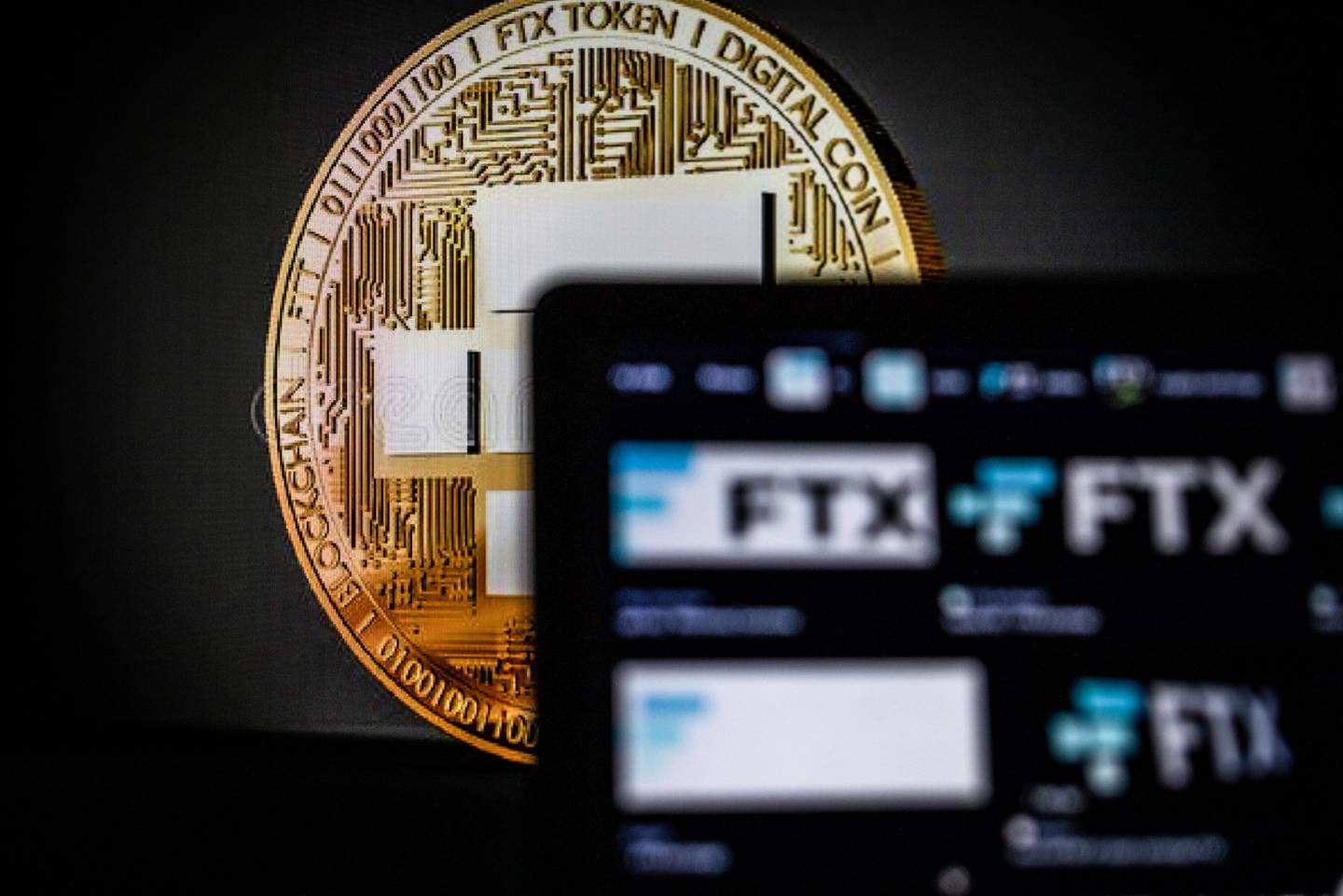 Una moneda que representa la criptomoneda Bitcoin más allá de los logotipos de FTX en un ordenador portátil. Fotógrafo: Ángel García/Bloombergdfd