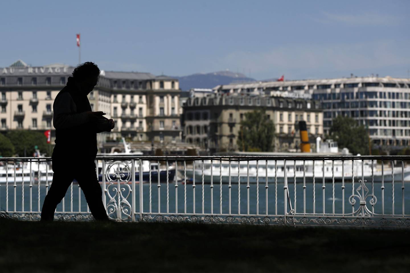 Un peatón camina a lo largo de las orillas del lago de Ginebra, también conocido como Lago Leman, en Ginebra, Suiza, el martes 14 de mayo de 2019.