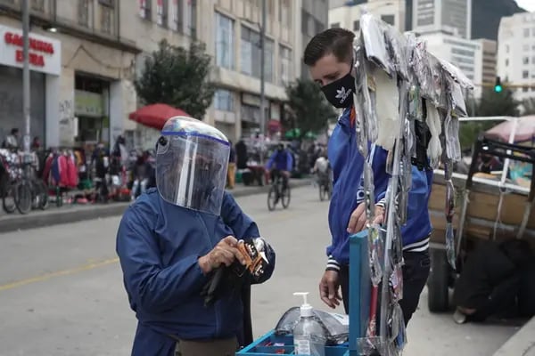 Una persona que usa una máscara protectora y un protector facial compra guantes en el centro de Bogotá, Colombia, el martes 16 de junio de 2020