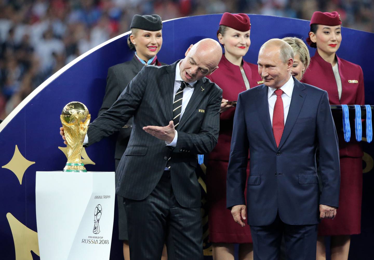 Gianni Infantino, left, gestures toward the World Cup trophy as Vladimir Putin prepares to award the trophy to France following the FIFA World Cup final match in Moscow in 2018.