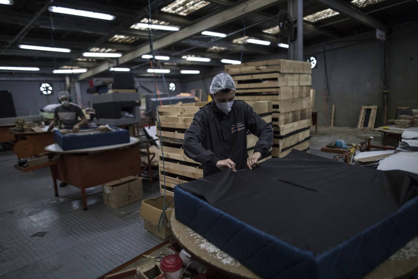 Un empleado con una máscara protectora ensambla un marco de sofá en una fábrica de Espumados SA en Soacha, Colombia, el lunes 27 de abril de 2020.