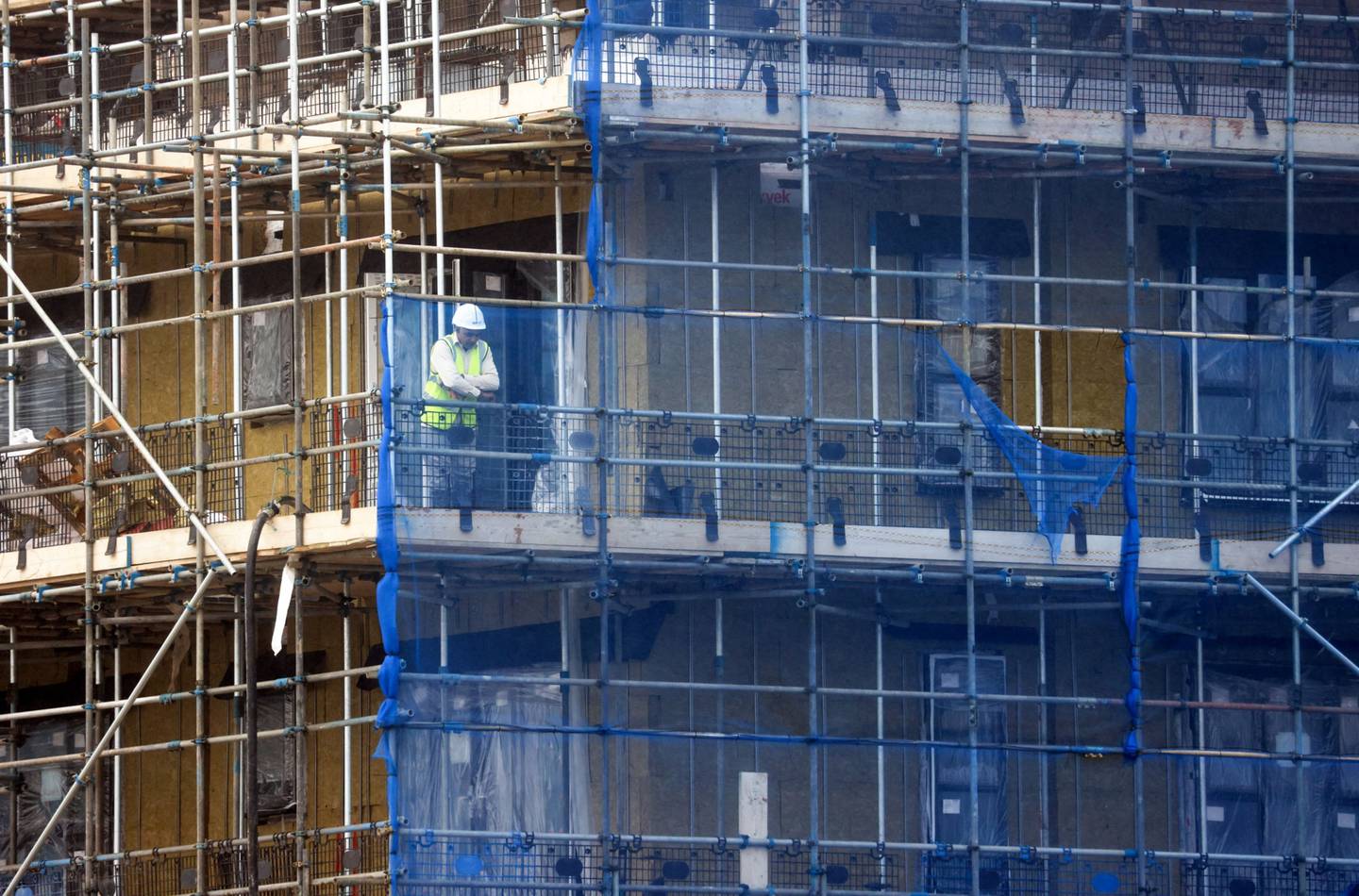 Un trabajador mira desde un andamio en un sitio de construcción.