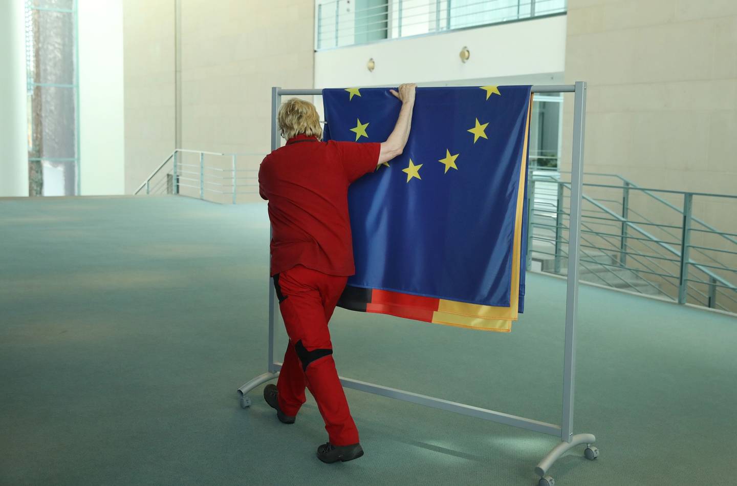 BERLÍN, ALEMANIA - 17 DE ABRIL: Un trabajador enrolla banderas, incluidas las de Alemania y la Unión Europea, tras la visita de Estado de la primera ministra de Nueva Zelanda, Jacinda Ardern, en la Cancillería el 17 de abril de 2018 en Berlín, Alemania. (Foto de Sean Gallup/Getty Images)
