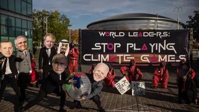 Activistas ambientales del Equipo de Acciones de Glasgow, participan en una manifestación con el tema de "Squid Games", con máscaras que representan a líderes mundiales, durante las conversaciones climáticas de la COP26.