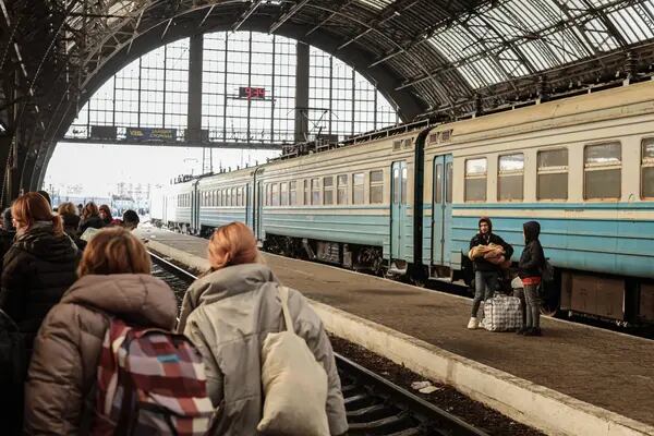 Um casal ucraniano deslocado e uma criança a caminho da Polônia esperam na estação ferroviária de Lviv-Holovnyi em Lviv, Ucrânia