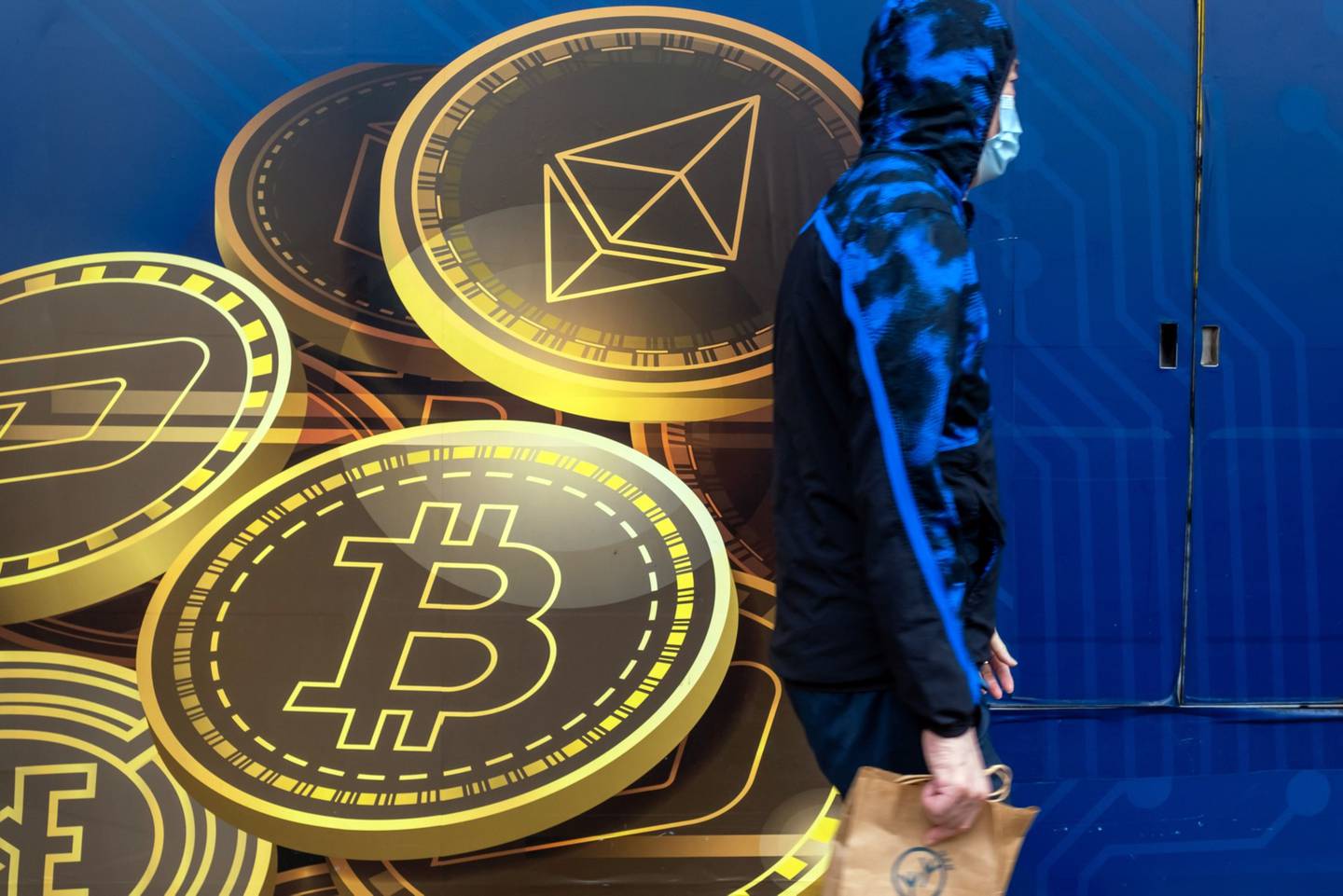 Un persona pasa por delante de un anuncio de Ethereum y bitcoin afuera de la tienda de comercio de moneda digital Hong Kong Digital Asset Exchange Ltd.