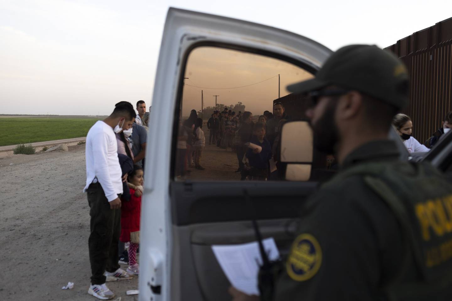 Migrantes en busca de asilo esperan a ser procesados por agentes de la Patrulla Fronteriza de Estados Unidos después de cruzar la frontera entre México y Estados Unidos en Yuma, Arizona.dfd
