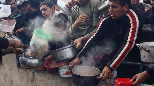 Palestinos sostienen contenedores para recoger alimentos gratuitos de un hospicio de voluntarios en Rafah, sur de Gaza, el domingo 17 de diciembre de 2023.