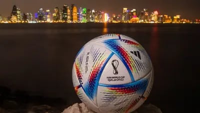 In this photo, an official FIFA World Cup Qatar 2022 ball sits on display in front of the skyline of Doha.