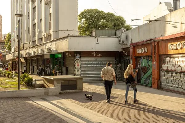 Pedestrians walk past shuttered stores in the Belgrano neighborhood of Buenos Aires.