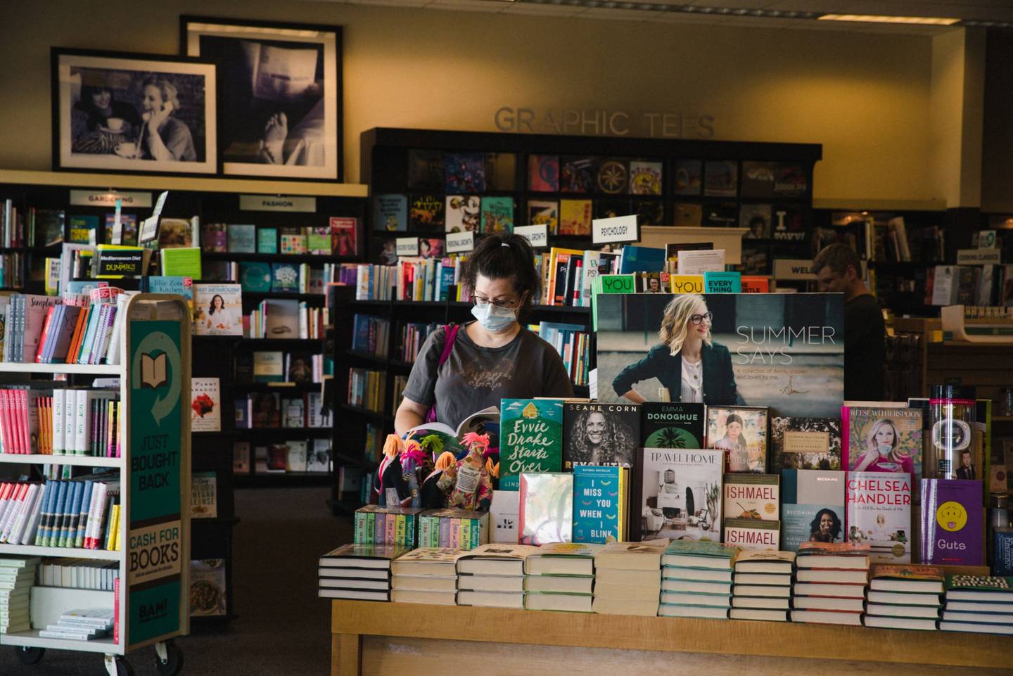 Un comprador con una máscara protectora lee dentro de una tienda de Books-A-Million Inc. en el reabierto Anderson Mall en Anderson, Carolina del Sur, el viernes 24 de abril de 2020.