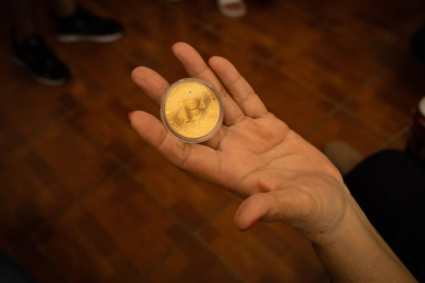 Una persona sostiene un token de Bitcoin en el cajero automático (ATM) de Bitcoin en El Zonte, El Salvador.