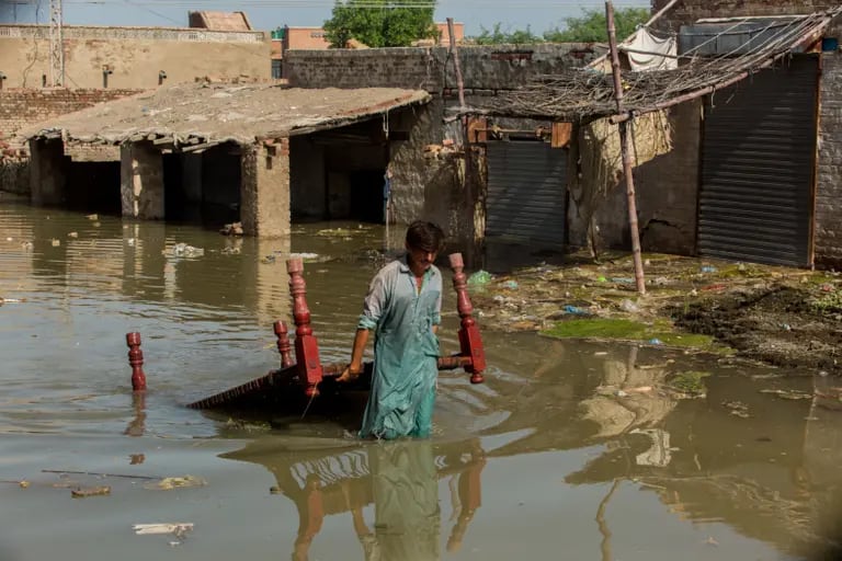 Hombre caminando por una inundación en Pakistándfd