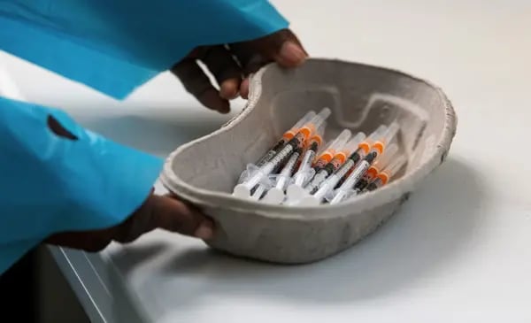 Un trabajador sanitario coloca un plato de jeringuillas cerca de un vial de la vacuna Covid-19, producida por Pfizer Inc. y BioNTech SE.