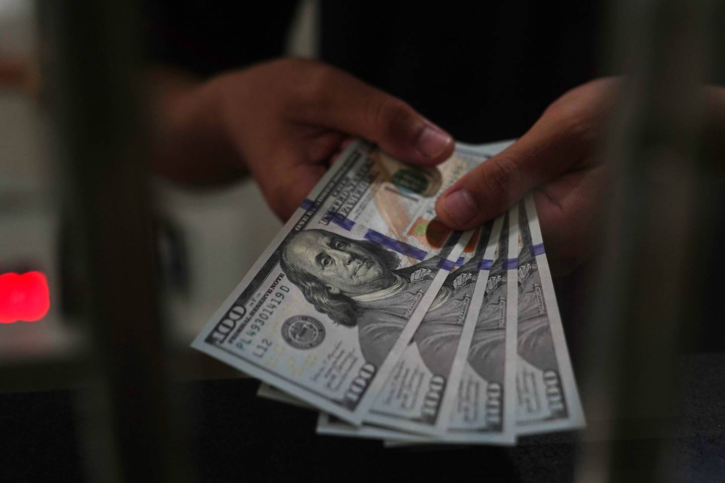 Una persona sostiene billetes de dólares estadounidenses en una oficina de cambio.
