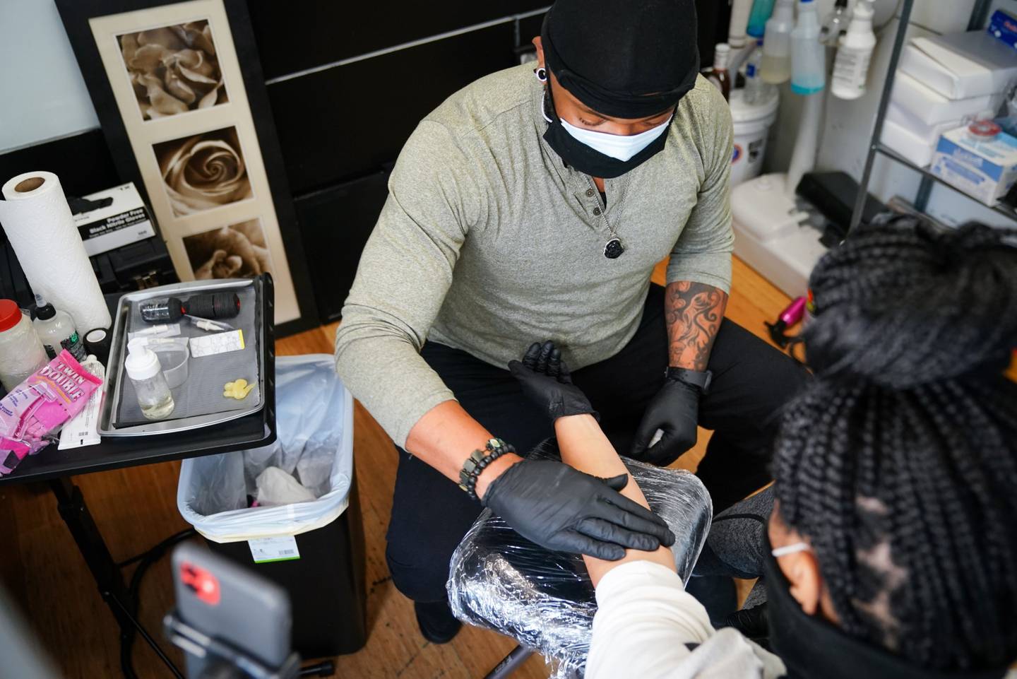 Un artista del tatuaje con una máscara protectora trabaja limpia el brazo de un cliente en un salón de tatuajes en Atlanta, Georgia, Estados Unidos, el viernes 24 de abril de 2020. Fotógrafo: Elijah Nouvelage/Bloomberg