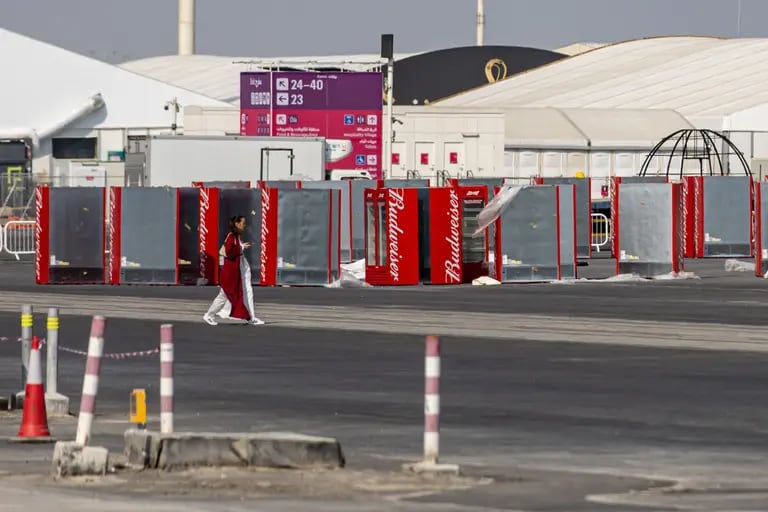 Unos trabajadores pasan junto a unas neveras de Budweiser en el exterior del estadio de Lusail, en Doha (Qatar).dfd