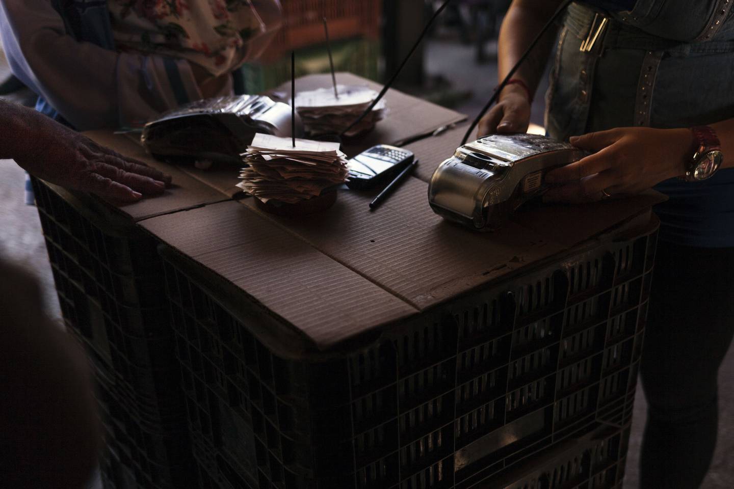 A vendor operates a credit card machine at a street market in the La Urbina neighborhood of Caracas, Venezuela