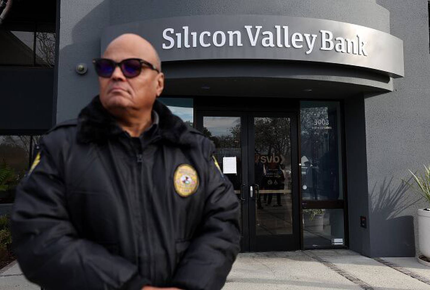 Un guardia de seguridad del Silicon Valley Bank vigila una fila de personas fuera de la oficina el 13 de marzo de 2023 en Santa Clara, California.