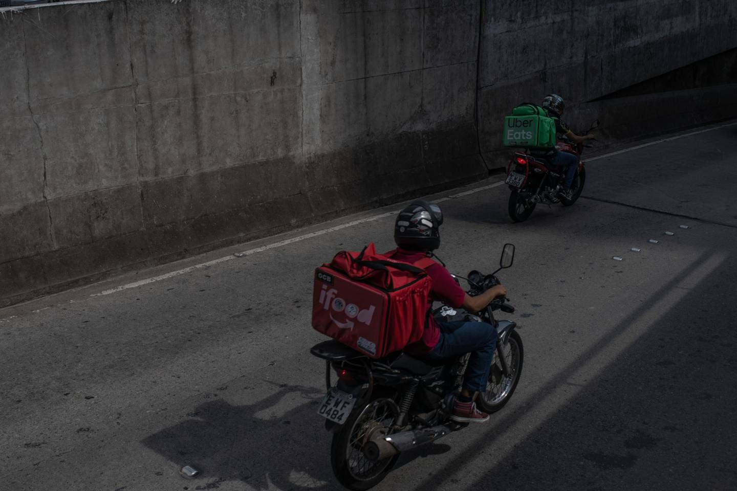 Trabajadores con mochilas aislantes de iFood y Uber Eats montan en motocicletas mientras hacen entregas en Sao Paulo, Brasil, el miércoles 1 de abril de 2020.dfd