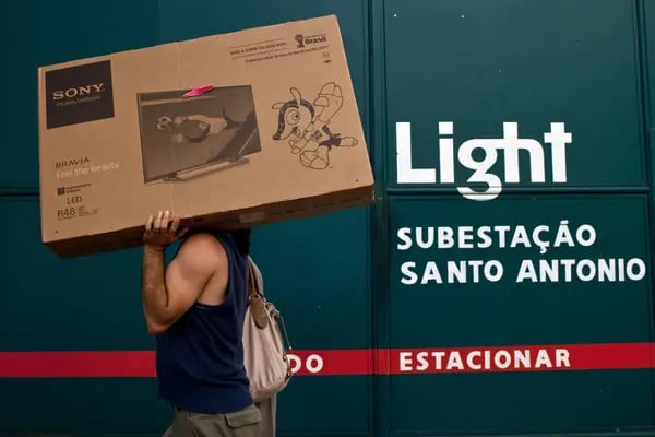 Un hombre lleva una caja de televisión de pantalla plana frente a una subestación eléctrica de Light SA en Río de Janeiro, Brasil, el martes 11 de febrero de 2014.  Fotógrafo: Dado Galdieri/Bloomberg