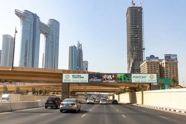 Automovilistas pasan por debajo de un anuncio digital de la Expo 2020 Duabi en la calle Sheikh Zayed, en el centro de Dubai, Emiratos Árabes Unidos, el martes 28 de septiembre de 2021. La feria mundial se celebrará entre el 1 de octubre y el 31 de marzo, tras haberse retrasado un año debido a la pandemia del Covid-19.