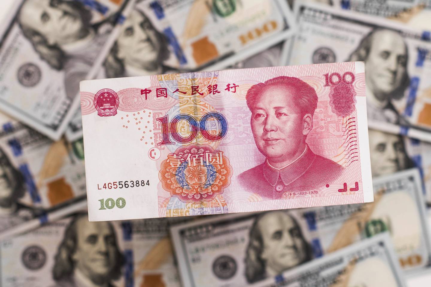 Un billete chino de cien yuanes sobre una pila de billetes de cien dólares estadounidenses en esta fotografía arreglada tomada en Hong Kong, China, el lunes 20 de julio de 2015.