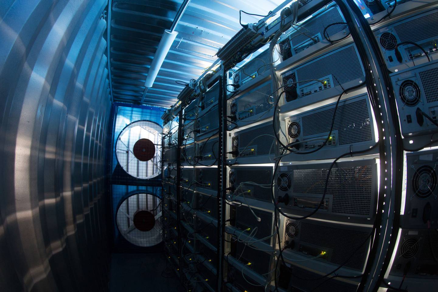 Los ventiladores de refrigeración operan junto a las plataformas mineras dentro de un contenedor de envío convertido en una granja minera de criptomonedas móvil.