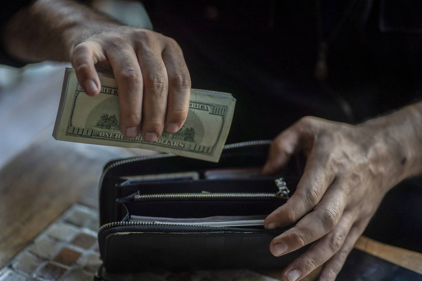 A person with U.S. dollar banknotes and a purse.
