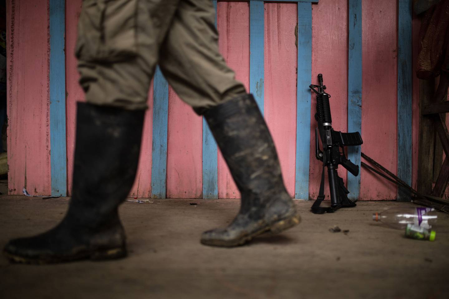Un guerrillero del Ejército de Liberación Nacional (ELN) pasa junto a un arma apoyada en una pared en un pueblo remoto en el departamento de Chocó, Colombia, el viernes 17 de noviembre de 2017.