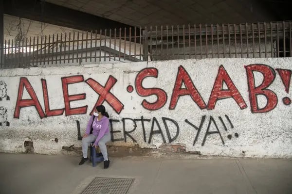 A pedestrian wearing a protective mask sits near a wall with graffiti that reads in Spanish "Free Alex Saab Now!" in the Petare neighborhood of Caracas, Venezuela, on Thursday, Feb. 4, 2021. President Nicolas Maduro's Colombian financier Alex Saab is being labeled "the peoples savior" in new graffiti across Caracas ahead of a key hearing Friday on his alleged role in bribing Venezuelan officials. Photographer: Carlos Becerra/Bloomberg