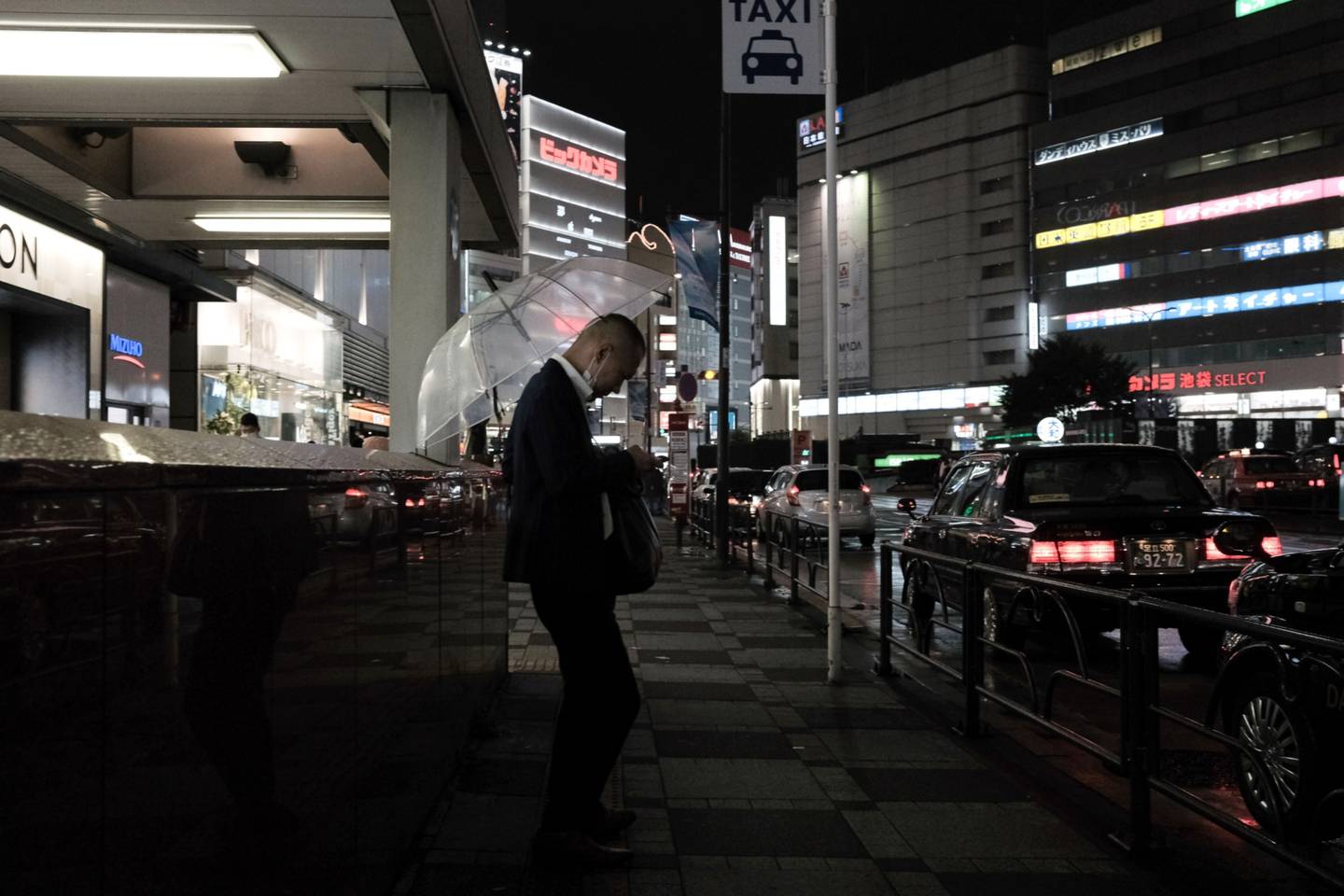 Un viajero nocturno mira un teléfono en una parada de taxis en Tokio, Japón, el viernes 13 de agosto de 2021.