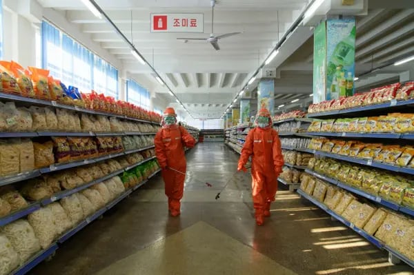 Empleados rocían desinfectante como parte de las medidas preventivas contra el Covid-19 en los almacenes Yokjon en Pyongyang, el 20 de octubre de 2021.